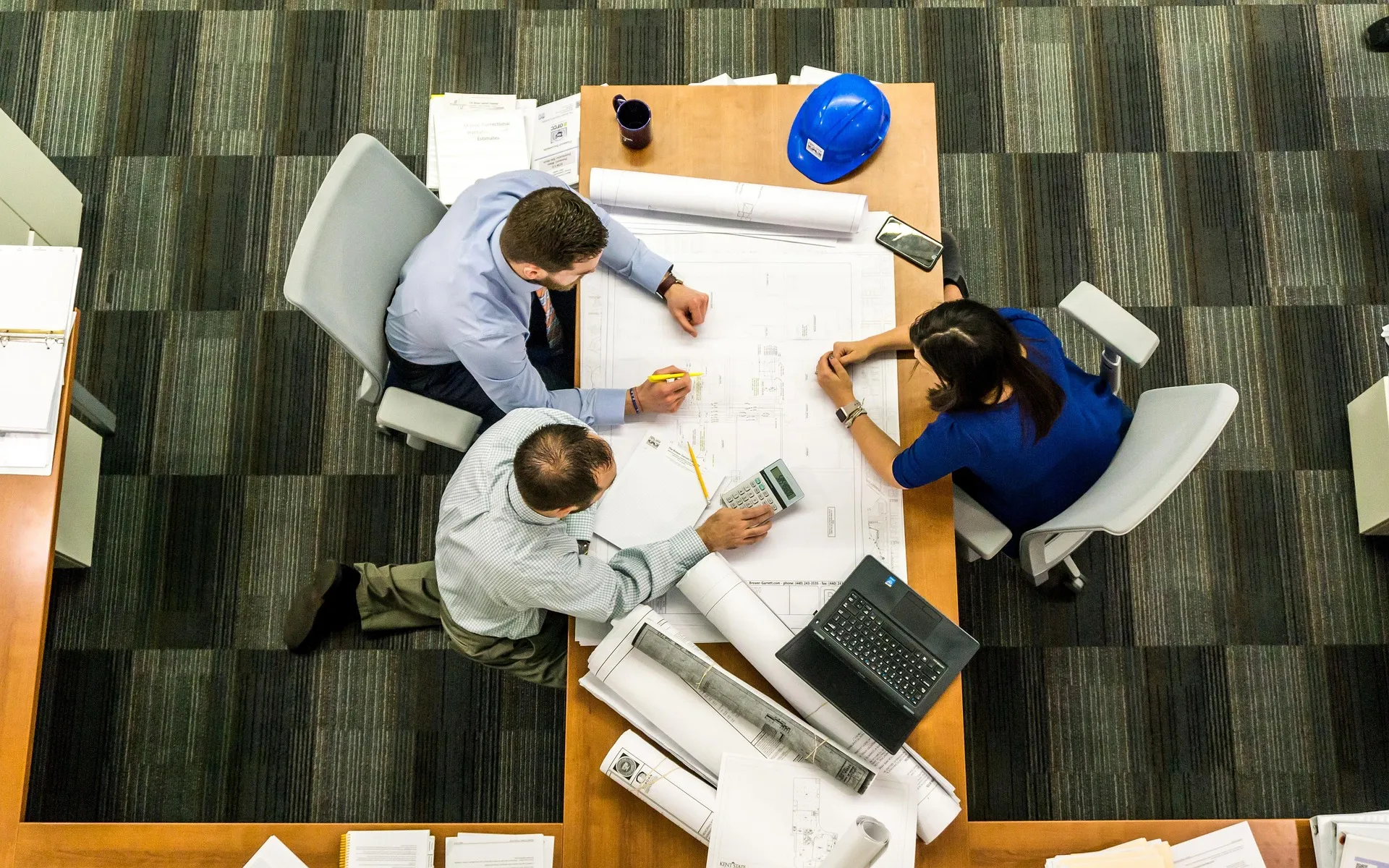 Engineers reviewing drawings together around a table