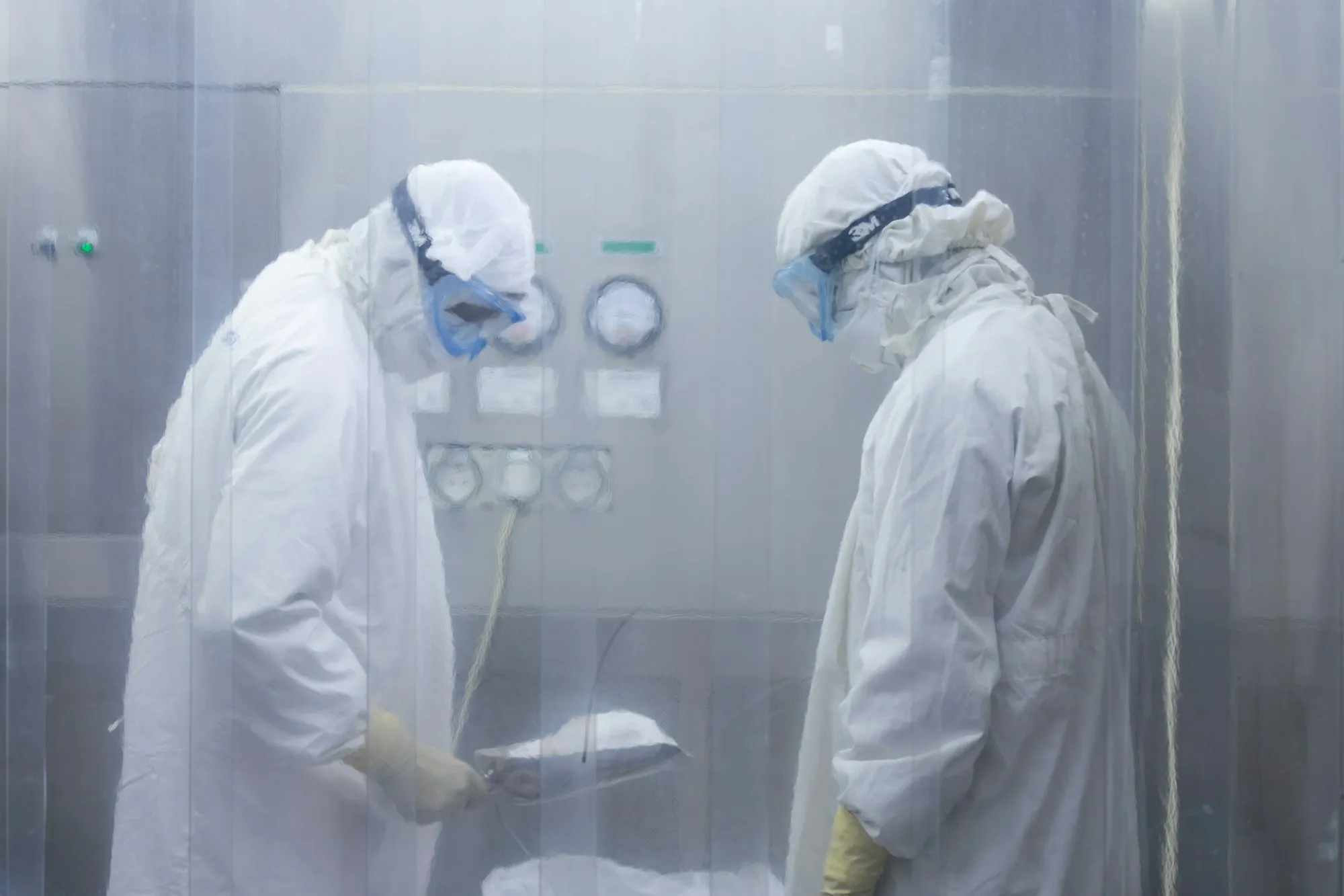 Gowned operators working at a pharmaceutical process panel